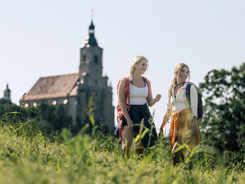 Wanderer bei der Wallfahrtskirche Pöllauberg in der Oststeiermark © Oststeiermark Tourismus | Bernhard Bergmann 